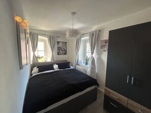 A bedroom with a bed, a wardrobe, a window with curtains, a plant, and a wall-mounted light fixture. - FarawayHomes Studios Schwertberg (Schwertberg)