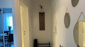 Un couloir avec une porte en bois, un banc et une plante en pot.