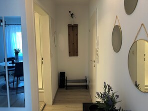 Un pasillo con puerta de madera, un banco y una planta en maceta.