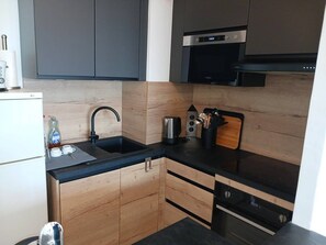 Eine kleine Küche mit Spüle, Kaffeemaschine und Mikrowelle.