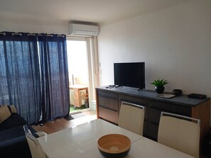 Ein modernes Wohnzimmer mit Flachbildfernseher, einem Esstisch und einer Couch.