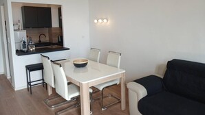 A compact living space with a kitchenette, a dining table with chairs, and a sofa. - Apartment sea view, AC - 4 guests (Canet-en-Roussillon)
