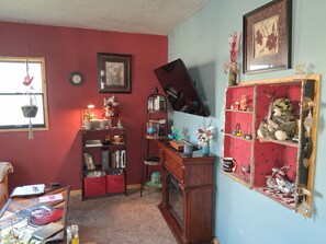 Ein Zimmer mit roter Wand, einem Holztisch, einem Bücherregal, einem Globus und einem Motorradregal.