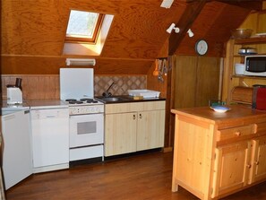 Eine kleine Küche mit Herd, Backofen, Mikrowelle und Holzschränken.