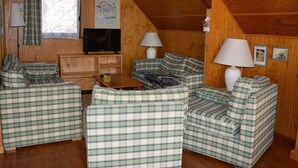 Un intérieur de chalet chaleureux, avec des meubles à motifs écossais, un téléviseur et des murs en bois.