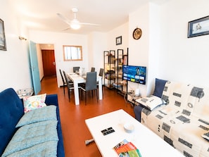 A living room with a sofa, a coffee table, a TV, and a dining area with chairs and a table. - Duplex Apartment for 6, Near Beach, Narbonne (Narbonne)