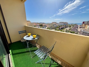 A balcony with a table and chairs, a view of the cityscape, and a clear sky. - Duplex Apartment for 6, Near Beach, Narbonne (Narbonne)