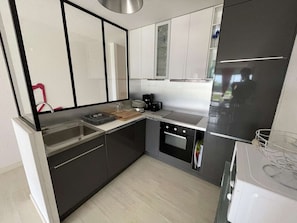 Eine moderne Küche mit Einbauofen, Kaffeemaschine und Spüle.