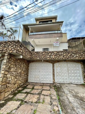 A two-story building with a stone facade, a balcony, and two garage doors.