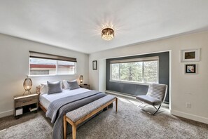 A bedroom with a large bed, bedside tables, a bench, a chair, and a window with a view. - 4 Bedrooms, Lakeviews, Hot Tub, Pool Table! (South Lake Tahoe)
