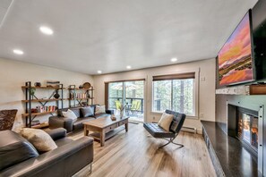 Una sala de estar moderna con chimenea, un televisor de pantalla plana grande y una estantería.
