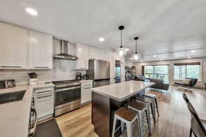 A modern kitchen with stainless steel appliances, a central island, and bar stools. - The Heavenly Retreat, 4 Bedrooms  Lakeviews, Hot Tub, Pool Table! (South Lake Tahoe)