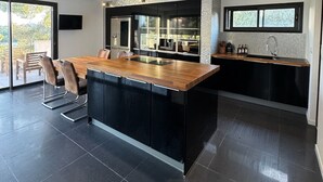A modern kitchen with a central island, black cabinetry, and a large window. - TOULON ARCHITECT-DESIGNED VILLA (Toulon)
