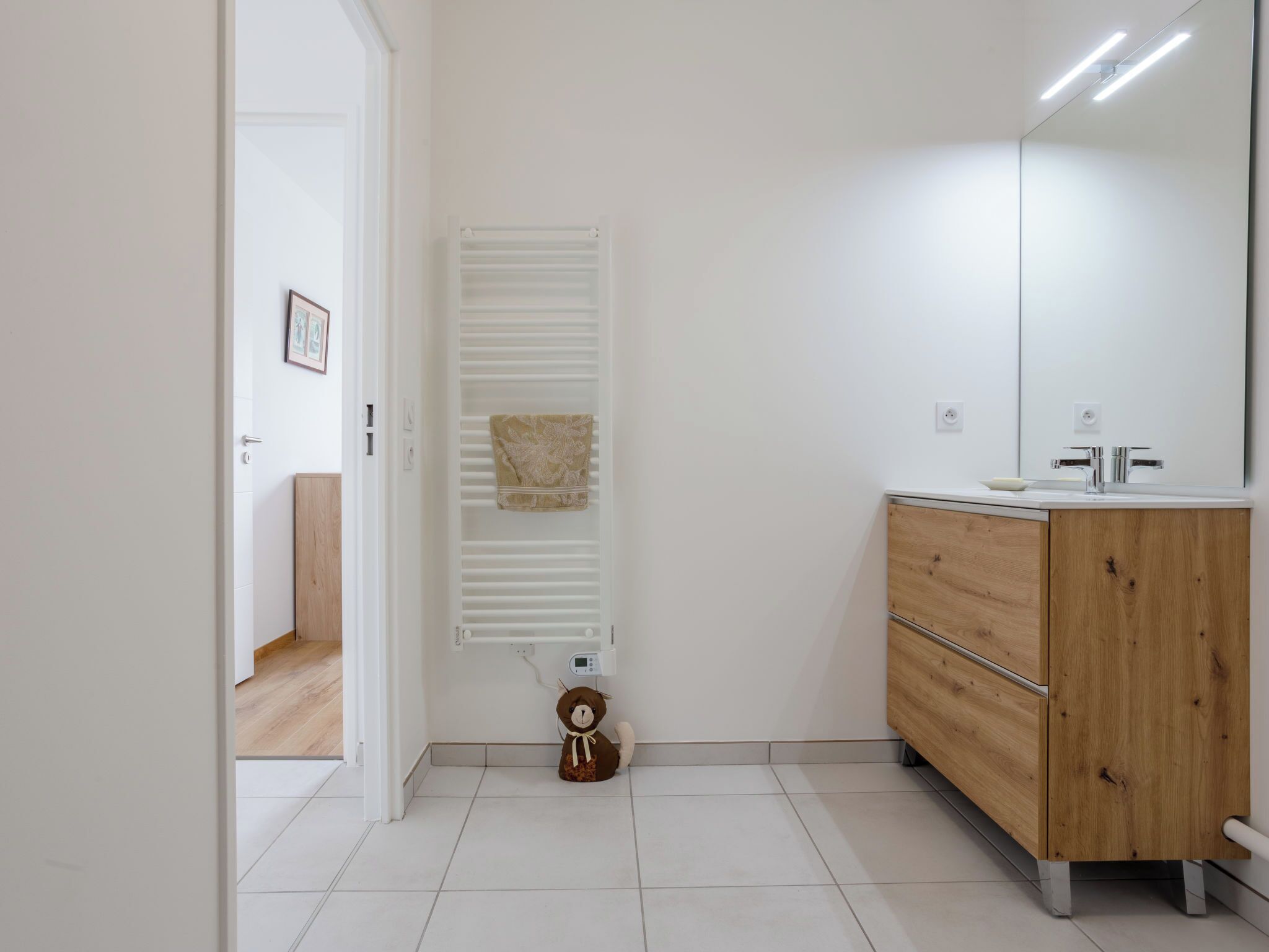 A bathroom with a wooden vanity, a mirror, a towel rack, and a radiator.