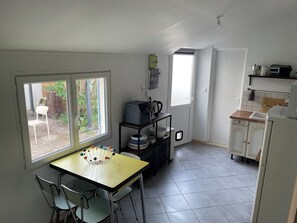 A compact kitchen with a dining table and chairs, a small cabinet, and a window with a view of the outside. - Charming house facing the Atlantic, garden and pergola 2 min from beaches (Fouras)
