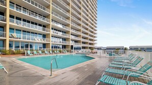 Uma área de piscina no terraço, com uma piscina grande, vários níveis de varandas e fileiras de espreguiçadeiras.