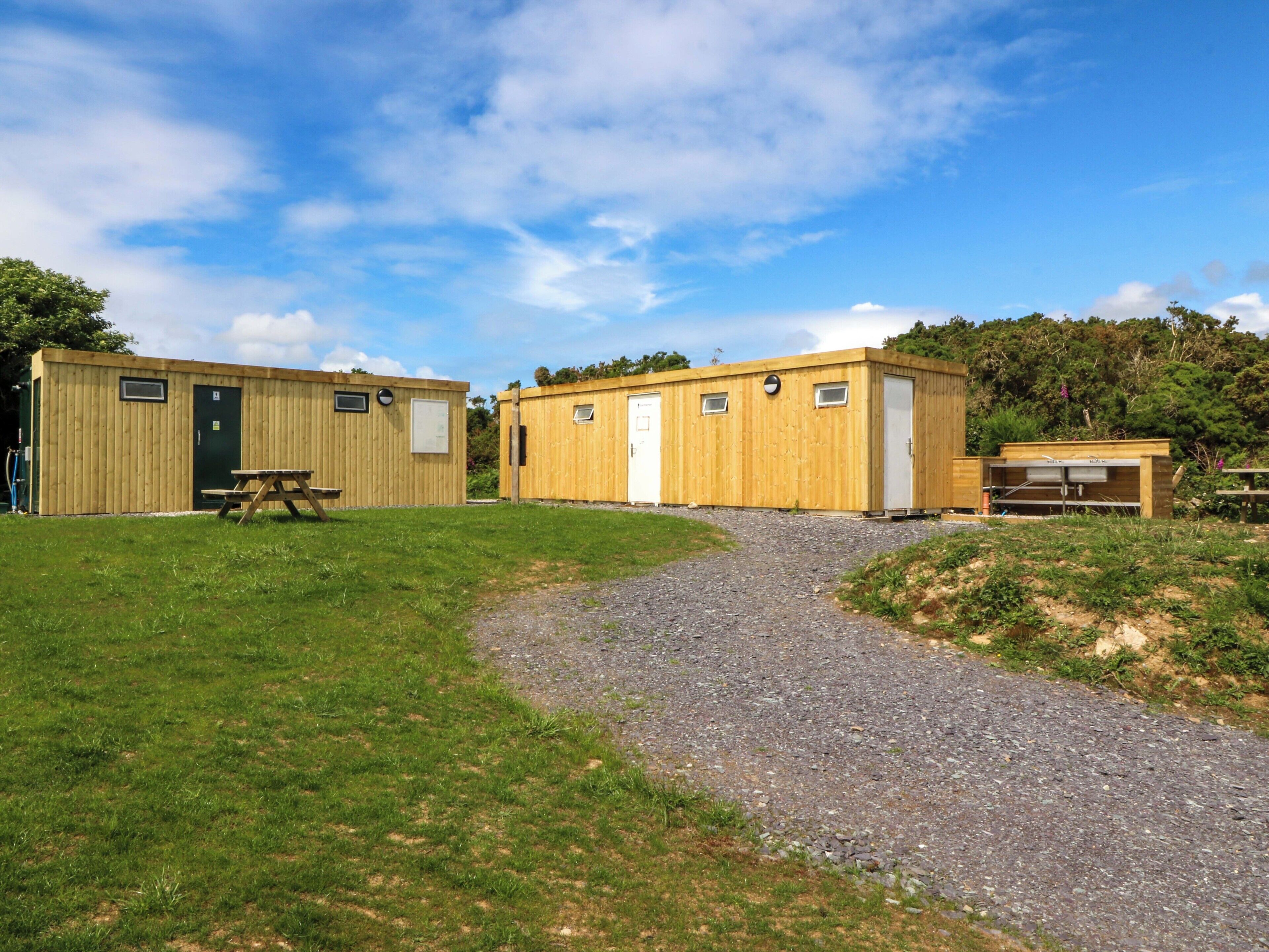 Un camping con dos cabañas de madera, una mesa de picnic y un camino de grava.