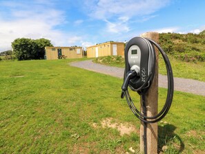 Una estación de carga para vehículos eléctricos en un área con césped y un sendero que conduce a un edificio.