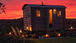 Una casetta di legno con una porta aperta, un piccolo portico e un lampione.