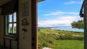 Una stanza con vista su un paesaggio erboso e un corpo d'acqua.