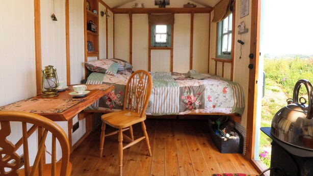 Accogliente camera con letto, sedia in legno, tavolo e vista sull'esterno.