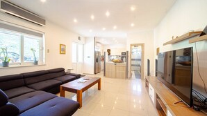 Una sala de estar moderna con un sofá, una mesa de centro, un televisor y una cocina al fondo.