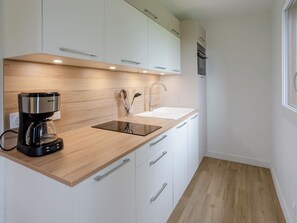 A modern kitchen with a coffee maker, a sink, and wooden cabinets. - Les Ducs de Normandie by Interhome (Houlgate)