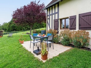 Ein Haus mit Terrasse, Tisch, Stühlen und Grill.