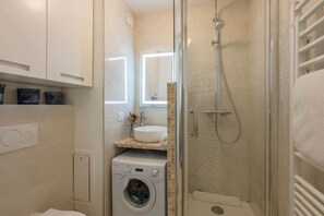 A compact bathroom with a washing machine, a sink with a mirror, and a shower enclosure. - L Chapp e Chamoniarde Centre of Chamonix (Chamonix-Mont-Blanc)