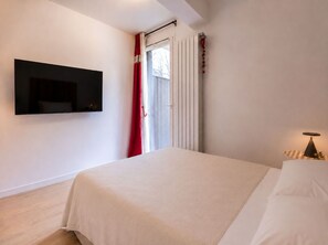 A bedroom with a bed, a TV mounted on the wall, a window with curtains, and a bedside lamp. - L Chapp e Chamoniarde Centre of Chamonix (Chamonix-Mont-Blanc)