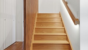 Eine Holztreppe mit einer weißen Wand und einer Holzwand links.