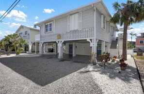 Ein zweistöckiges Haus mit Veranda, Kiesweg und einer Palme.