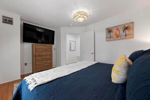 A bedroom with a bed, a television, a wardrobe, a door, and a painting on the wall. - Anna Maria Beach condo with hot tub (Holmes Beach)