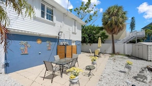 A patio area with outdoor furniture, a decorative wall, and a staircase leading to an upper level.