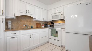 A modern kitchen with white cabinetry, a built-in oven, microwave, and a refrigerator.