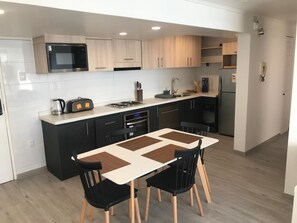 A modern kitchen with a central island, black cabinets, a microwave, and a refrigerator. - Oceanview Family Retreat in Vi a Laundry Parking (Vina del Mar)