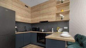 A modern kitchen with wooden cabinetry, a built-in oven, and a wooden countertop. - Modern Apartment with Parking | Balcony | Smart TV (Sosnowiec)