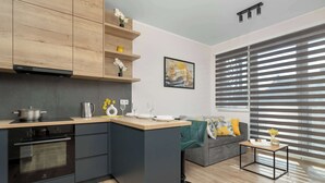 A modern kitchen with a built-in oven, a wooden countertop, and a grey island. - Modern Apartment with Parking | Balcony | Smart TV (Sosnowiec)