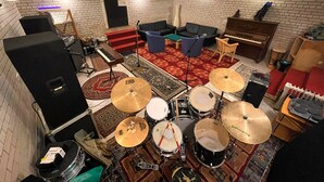 A room with a brick wall, a piano, a drum set, a keyboard, and a television. - Cozy accommodations on Lake Oberuckersee for larger groups (Flieth-Stegelitz)