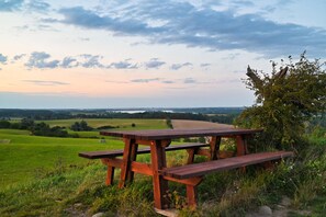Una mesa de picnic de madera en un campo verde con vistas a un paisaje lejano.