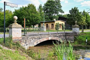 Eine Steinbrücke über einem Gewässer, auf der anderen Seite ein kleines Gebäude.