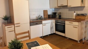A compact kitchen with white cabinetry, a wooden countertop, a built-in oven, and a dining table with chairs. - Cozy accommodations on Lake Oberuckersee for larger groups (Flieth-Stegelitz)