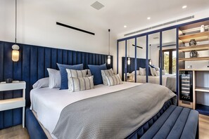 A modern bedroom with a large bed, bedside tables, a bench, and a wardrobe with mirrors. - Villa 'Carlini' with Sea View, Wi-Fi and Air Conditioning (Son Serralta)