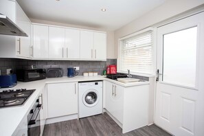 A compact kitchen with a washing machine, microwave, and gas stove.