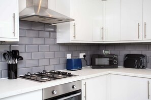 A kitchen with white cabinets, a gas stove, a toaster, and a microwave.