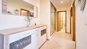Un pasillo con un mostrador de madera, un espejo y una puerta de cristal que da a otra habitación.