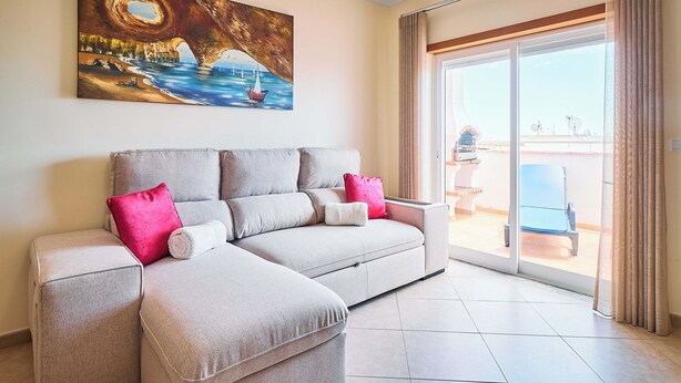 Una sala de estar con un sofá, un cuadro y vistas a través de un ventanal.