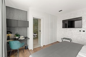 A modern bedroom with a bed, a desk with a chair, a TV mounted on the wall, and a wardrobe. - Villas Parenzo II (Kukci)