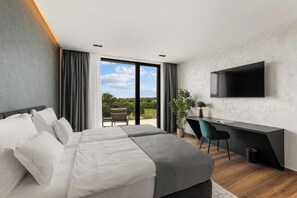 A modern hotel room with a large bed, a desk, a flat-screen TV, and a view of the outdoors. - Villas Parenzo II (Kukci)