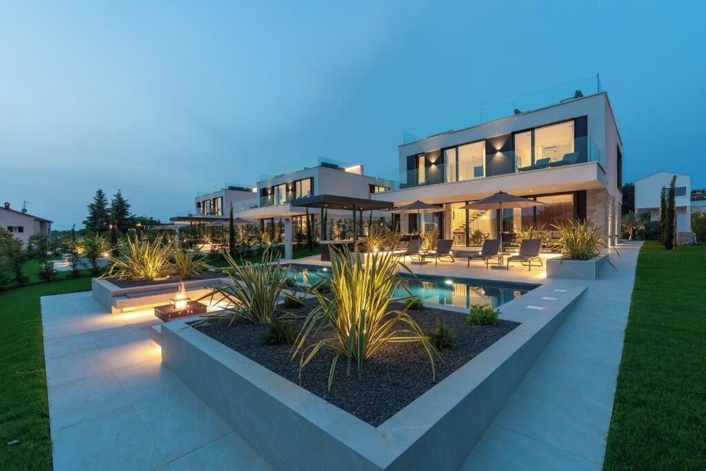 A modern two-story house with a swimming pool, outdoor seating, and a well-maintained garden.